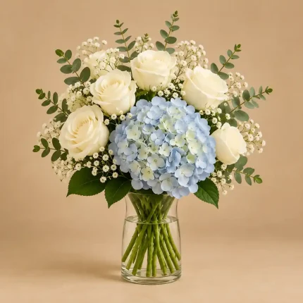 Blue hydrangea surrounded by white roses, baby's breath and eucalyptus in a floral arrangement