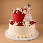 Two-tier bride cake with deep red and ivory tiers, piped roses, silver pearls, red and cream roses and bride figure