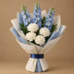 Blue delphiniums and white carnations with fresh greenery in ivory and blue wrapping
