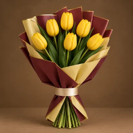 Six golden yellow tulips with fresh green foliage in maroon and warm-gold wrapping