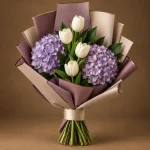 Two lavender hydrangeas and white tulips with deep green foliage in mauve and beige wrapping