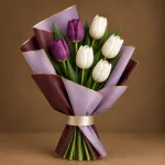 Purple and white tulip bouquet with green foliage and layered lavender and maroon wrapping